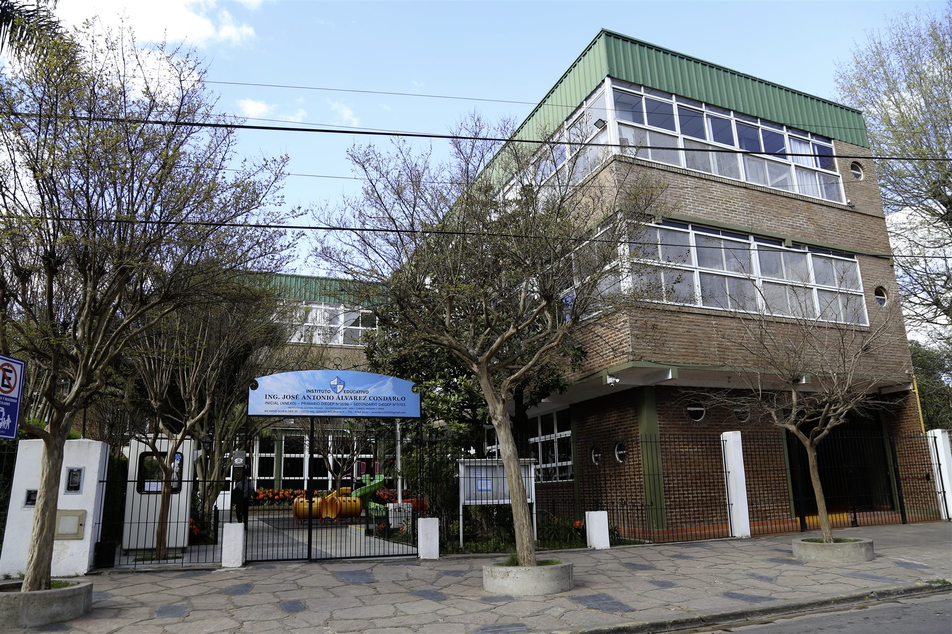 Fachada del colegio con su edificio de ladrillo y techo verde