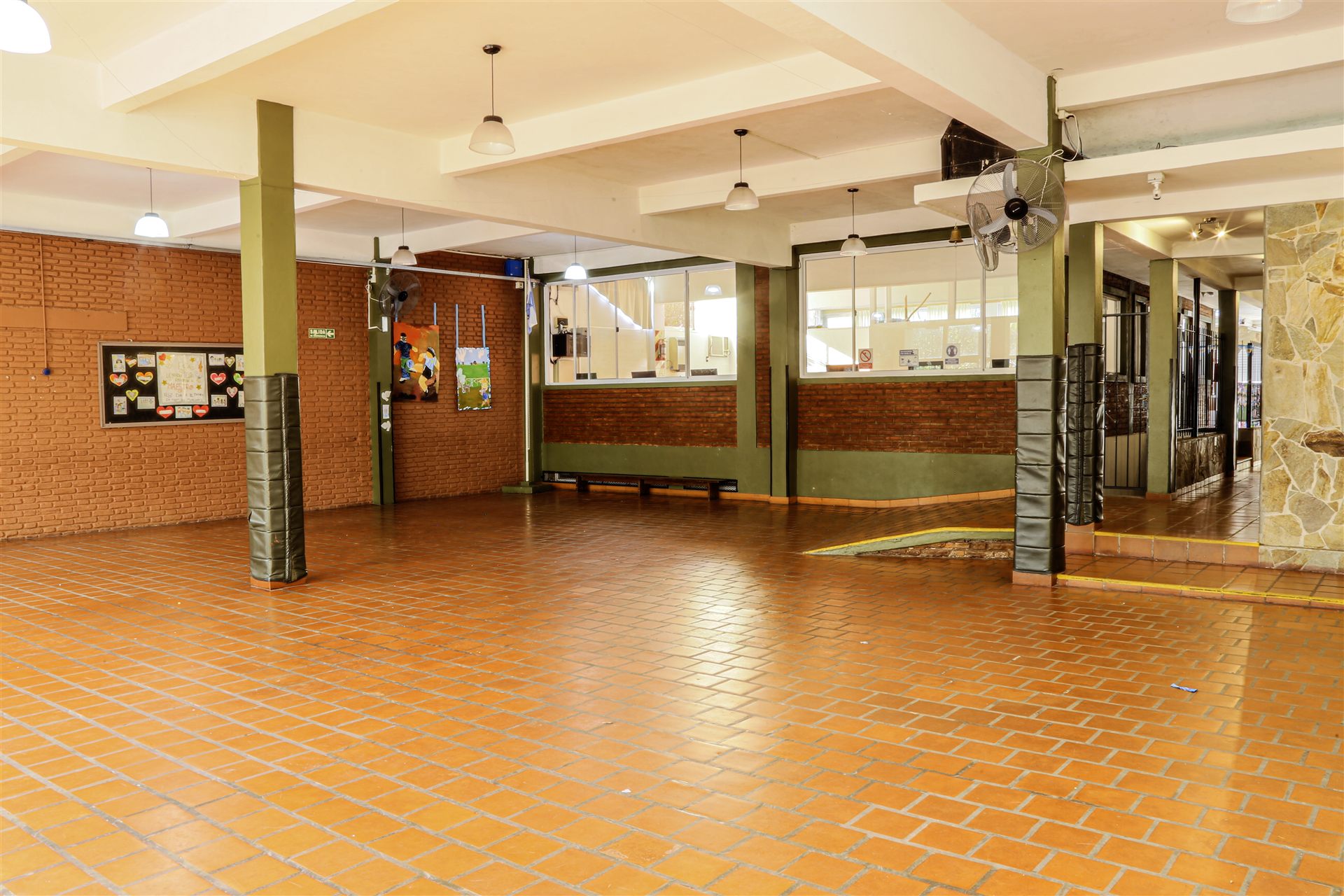 Hall cubierto con piso de cerámica, columnas verdes y carteleras
